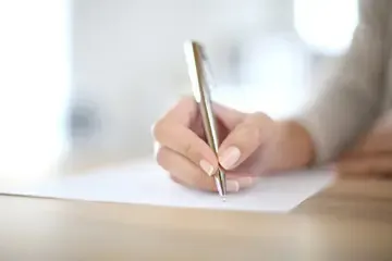 Close-up of a hand writing on paper with a pen