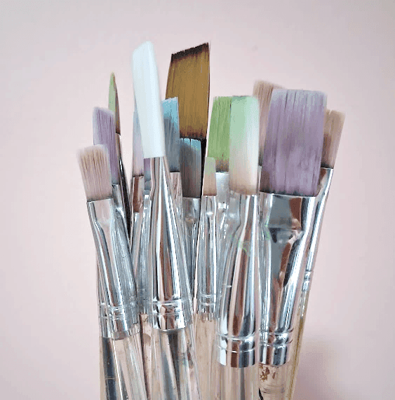 A collection of various artist paintbrushes in a jar